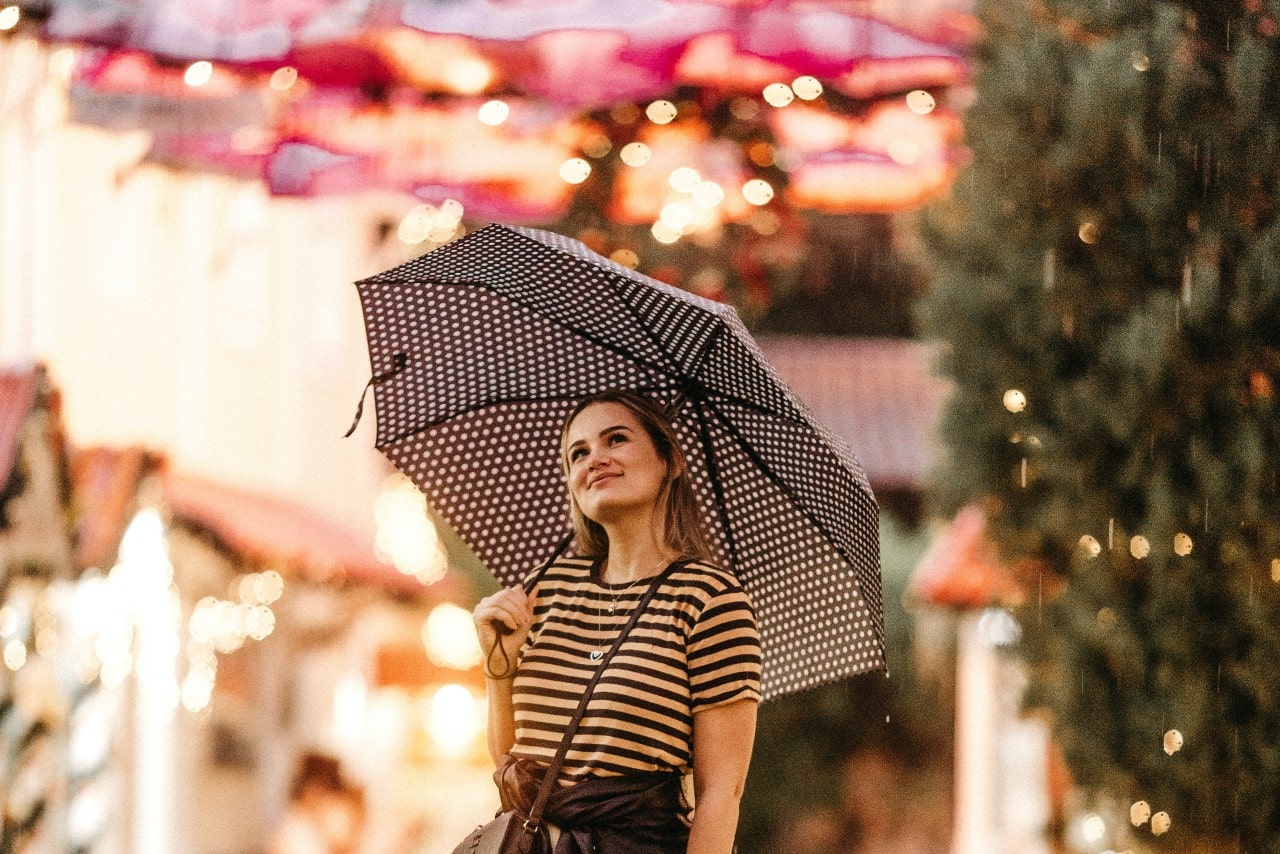 Stylish woman walking in the spring rain wearing multiple necklaces and earrings.