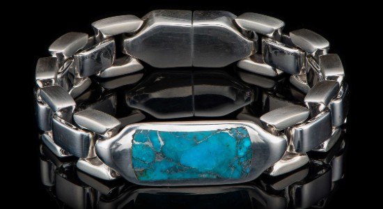 a silver toned watch with a large turquoise stone