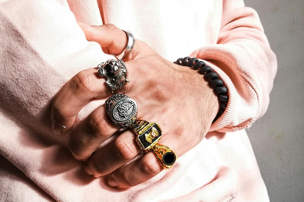 a man’s hand adorned with five bold fashion rings