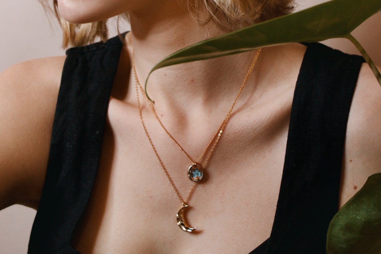 a woman’s neckline adorned with two rose gold necklaces of different lengths