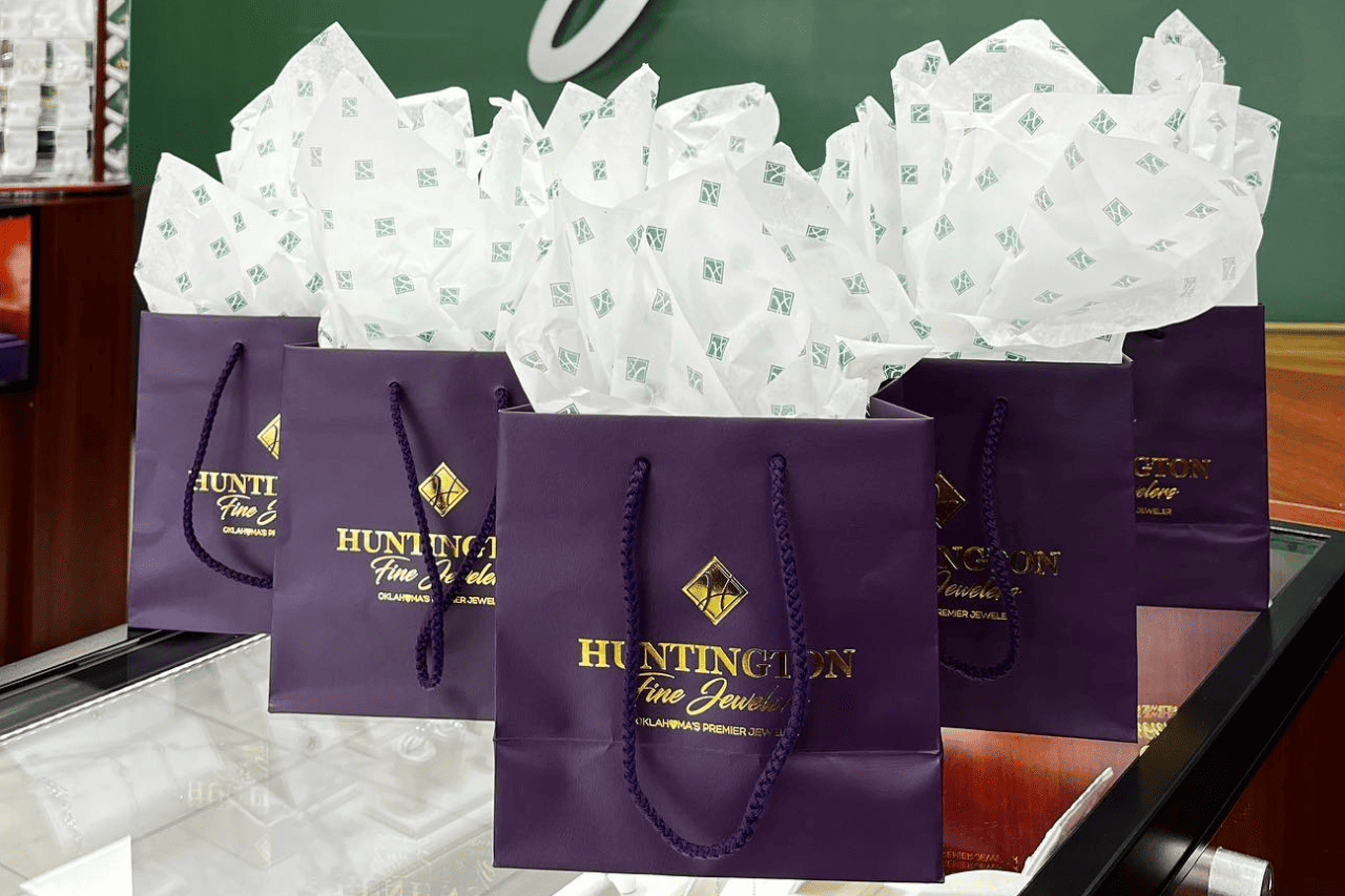 A close-up of 5 gift bags from Huntington Fine Jewelers, displayed atop one of their jewelry cases.