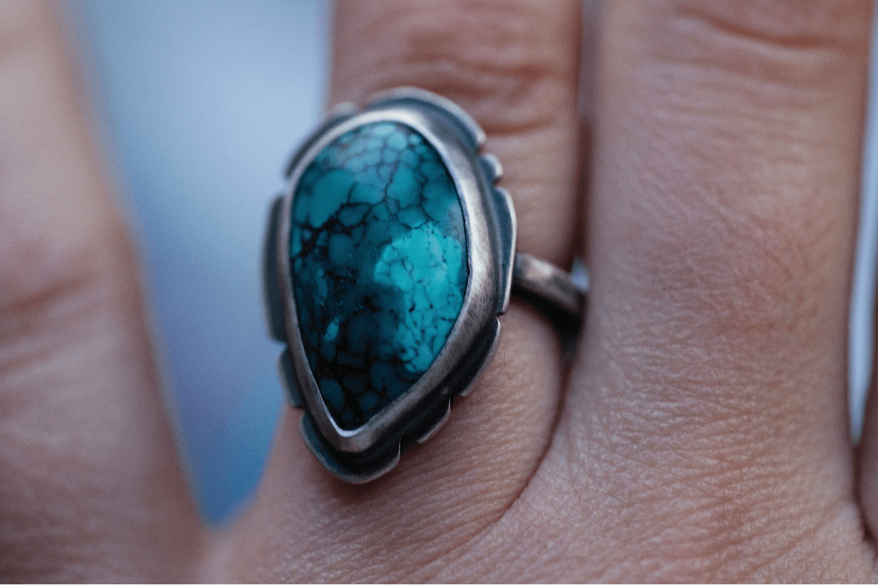 close up image of a silver and turquoise ring on a person’s hand close up image of a silver and turquoise ring on a person’s hand