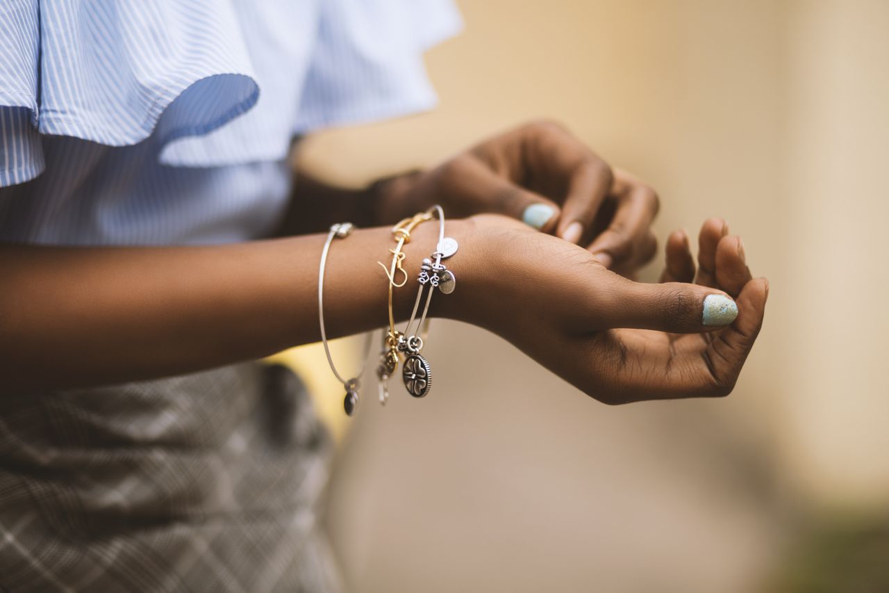 A close-up of a woman’s wrist, showcasing her mixed metal bracelets with charms.