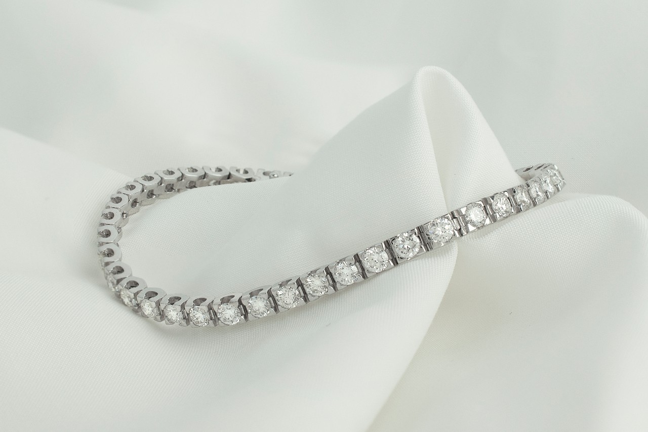 a white gold diamond line bracelet on a piece of white fabric a white gold diamond line bracelet on a piece of white fabric