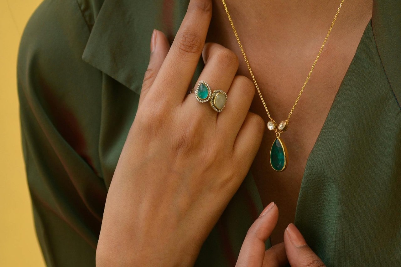 a woman wearing a green gemstone pendant necklace and a toi et moi fashion ring a woman wearing a green gemstone pendant necklace and a toi et moi fashion ring