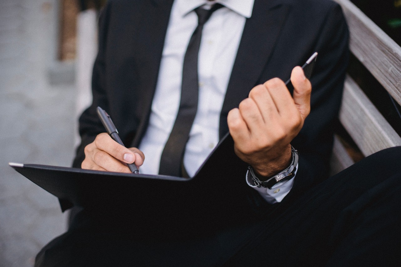 A businessman edits his proposal while wearing a watch outside. A businessman edits his proposal while wearing a watch outside.