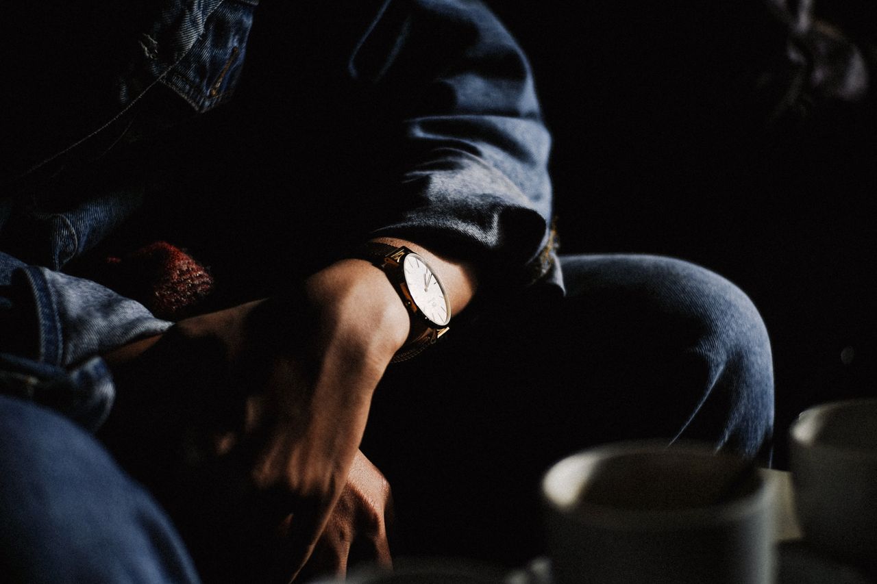 A man leans toward a coffee table with his mug, folding his hands with a watch. A man leans toward a coffee table with his mug, folding his hands with a watch.