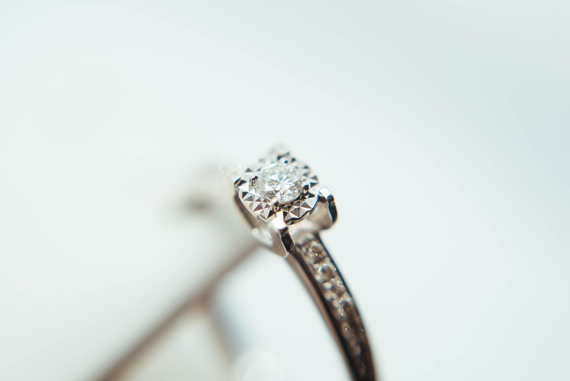 An elevated close-up of a solitaire engagement ring with side stones on a white background.