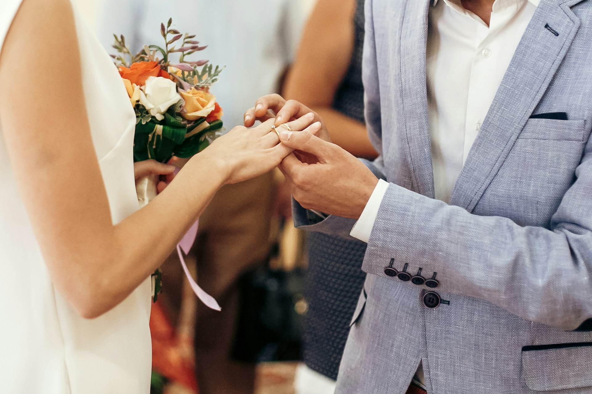 A groom placing a wedding band on his bride’s finger. A groom placing a wedding band on his bride’s finger.