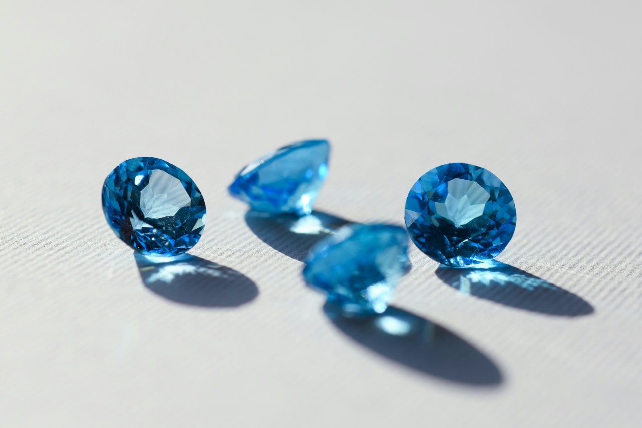 four round cut light blue gemstones sitting on a white surface four round cut light blue gemstones sitting on a white surface