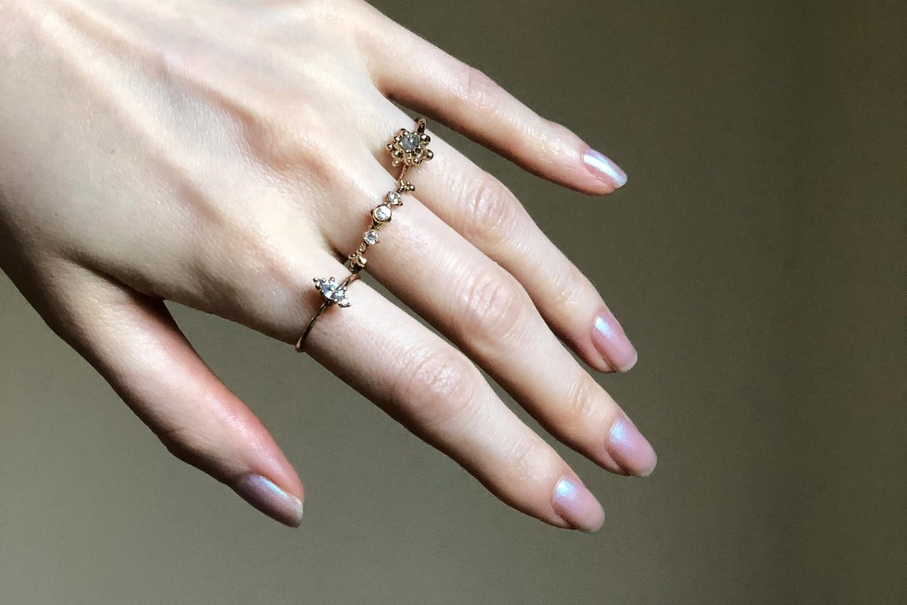 A close-up of a woman's hand, adorned with three delicate gold fashion rings. A close-up of a woman's hand, adorned with three delicate gold fashion rings.