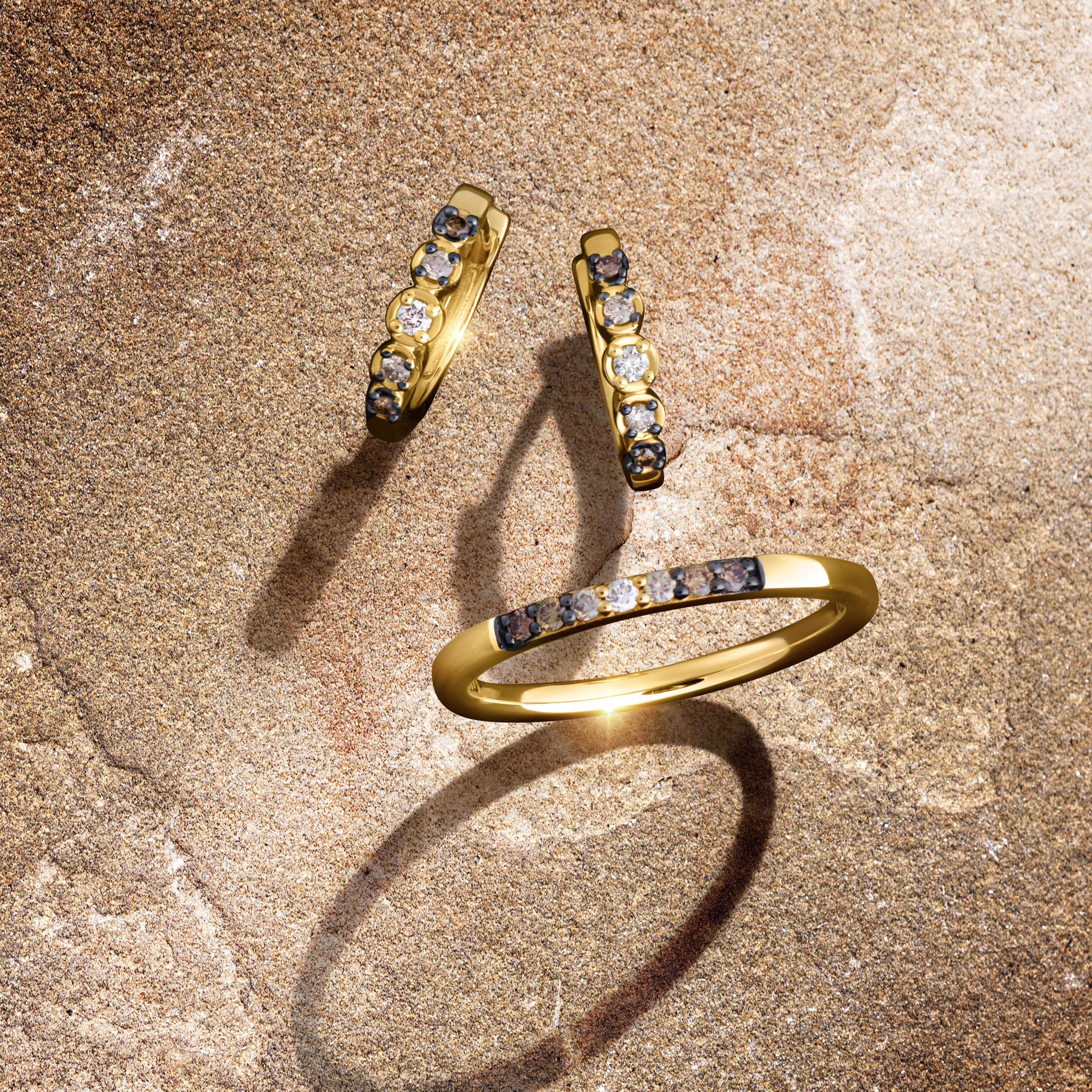 A close-up of a pair of dazzling diamond stud earrings on a dark, reflective backdrop.