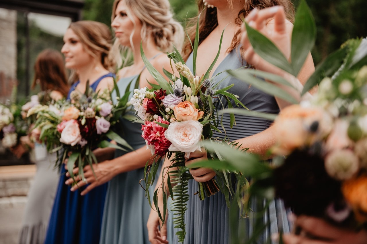 A low shot of 4 bridesmaids holding distinctive and colorful bouquets. A low shot of 4 bridesmaids holding distinctive and colorful bouquets.