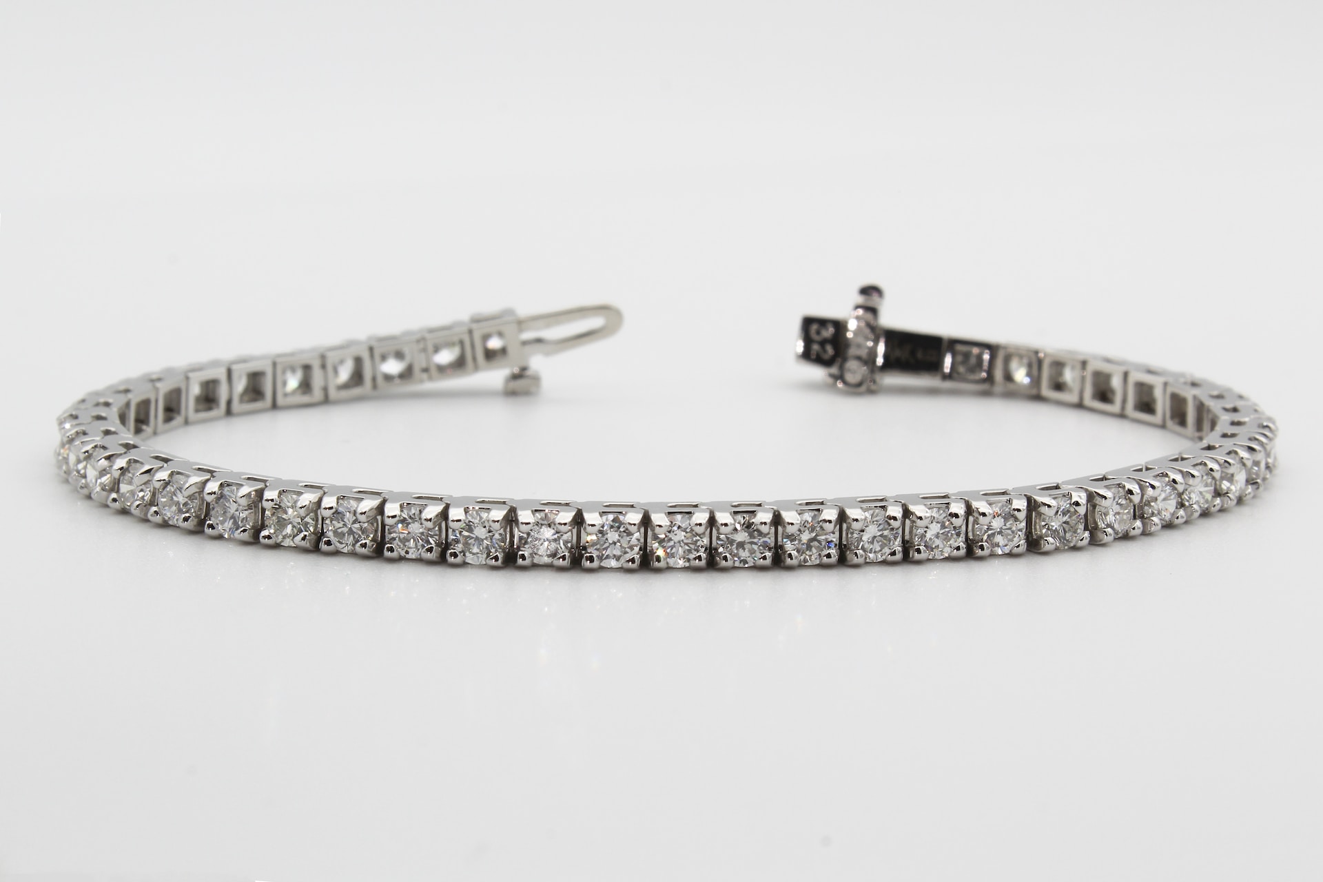 A sleek silver tennis bracelet adorned with a continuous row of sparkling square-cut diamonds.