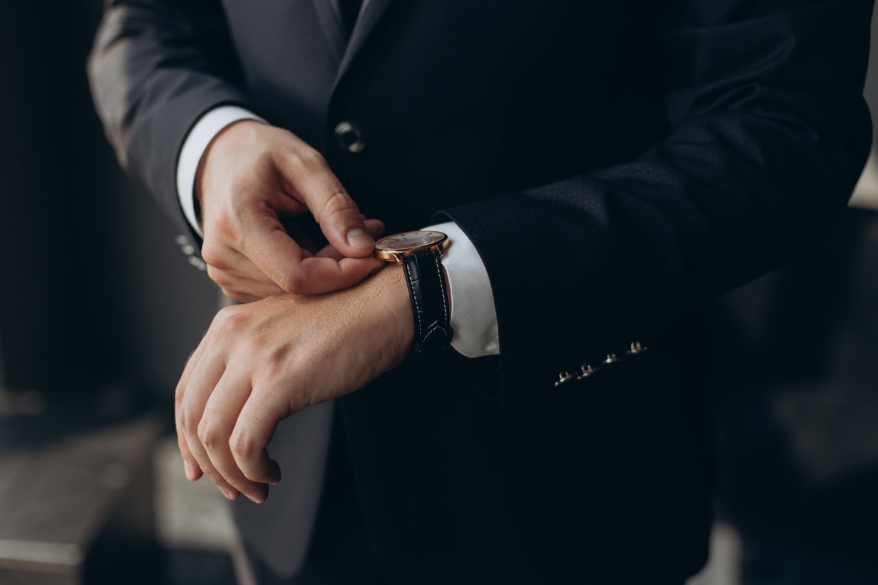 man in suit adjusting time on watch man in suit adjusting time on watch